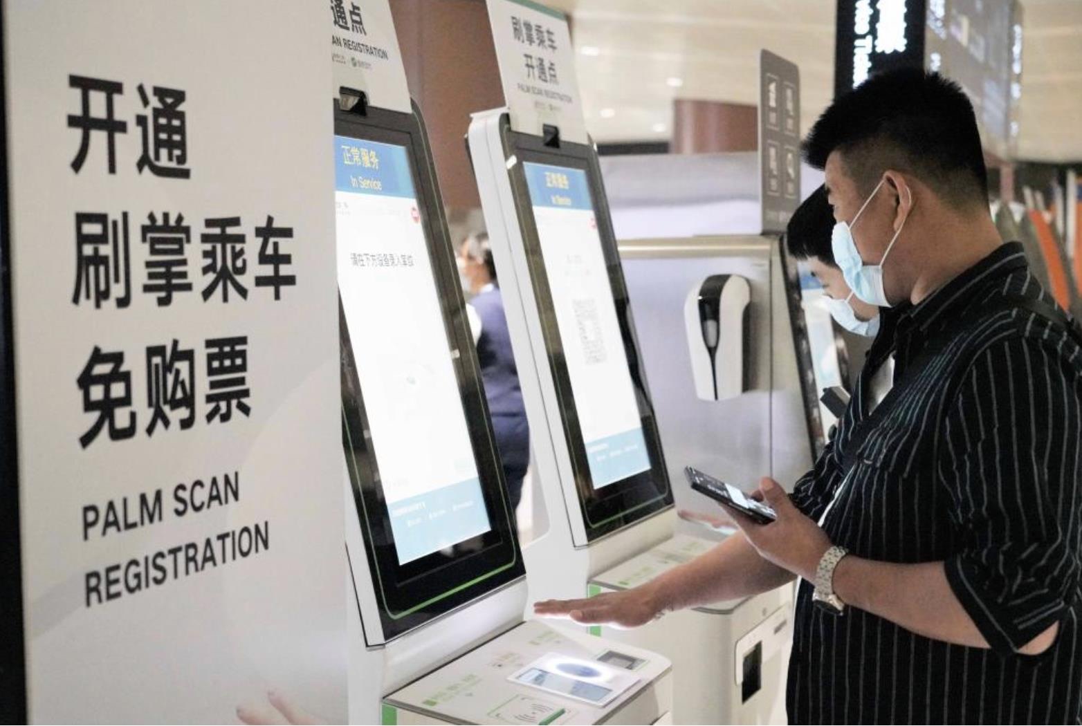 Commuters registering for palm scan fare payment at self-service kiosk in Daxing Metro station — showing registration process with 'Palm Scan Registration' signage