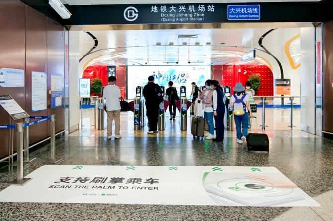 Beijing Daxing Airport Station entrance with palm scan turnstiles and commuters using palm recognition to enter — showing 'Scan the Palm to Enter' signage with Tencent PalmAI technology
